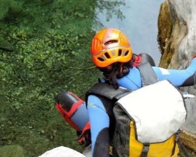 Escalando rocas con un casco naranja y un traje de neopreno azul, alguien abraza la emoción del barranquismo en Granada en el impresionante Barranco de Lentegí's, cerca de aguas cristalinas. - ForTwo - Planes para parejas