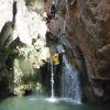 En una emocionante aventura, alguien desciende en rápel por una cascada entre cañones rocosos, exuberante vegetación y aguas cristalinas similar al Pack multiaventura en pareja en Madrid. - ForTwo - Planes para parejas