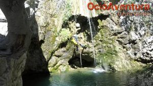 Un aventurero desciende en rápel por una cascada hasta una tranquila poza rocosa entre los escarpados acantilados de Jorox. Esta aventura con Barranquismo en Jorox de la mano de Ocio Aventura (Málaga) captura la esencia del ocio aventura en un entorno impresionante. - ForTwo - Planes para parejas