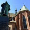 Ubicada en el histórico casco antiguo de Cracovia, una estatua adorna una clásica iglesia de ladrillo con ventanas arqueadas y techos verdes que brillan bajo un cielo azul claro, encarnando el encanto de este encantador barrio judío explorado durante la Visita guiada por el casco antiguo y el barrio judío (Cracovia). - ForTwo - Planes para parejas