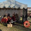 Dentro de una tienda, personas vestidas con trajes medievales disfrutan de la comida, evocando el pasado histórico de Toledo durante la Batalla medieval de arqueros; afuera, un hombre está listo con un escudo. - ForTwo - Planes para parejas