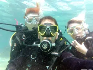 Tres buceadores con trajes de neopreno y gafas posan para un selfie grupal durante su "Bautizo de buceo con Freeandivers (Barcelona). - ForTwo - Planes para parejas