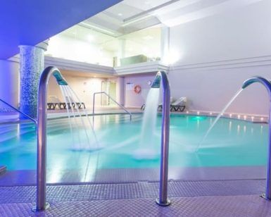 Sumérjase en una experiencia de piscina cubierta en Adeje, completa con cascadas de agua y tumbonas bajo una relajante iluminación azul, ideal para relajarse después de disfrutar del Circuito spa para 2 personas con opción de masaje. - ForTwo - Planes para parejas