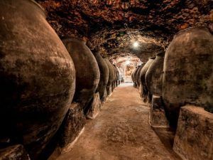 Explora la bodega subterránea, poco iluminada, en una visita guiada con tapas en Bodegas Peral (Madrid), donde grandes tinajas de barro adornan el estrecho pasadizo. Concluye el recorrido con deliciosas tapas para enriquecer tu experiencia. - ForTwo - Planes para parejas