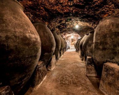Explora la bodega subterránea, poco iluminada, en una visita guiada con tapas en Bodegas Peral (Madrid), donde grandes tinajas de barro adornan el estrecho pasadizo. Concluye el recorrido con deliciosas tapas para enriquecer tu experiencia. - ForTwo - Planes para parejas