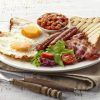Disfrute de un brunch romántico en el Restaurante Gaztedi-Berria, que ofrece un desayuno inglés completo con huevos, tocino, salchichas, frijoles, tostadas y ensalada servido en un plato blanco con cubiertos. - ForTwo - Planes para parejas