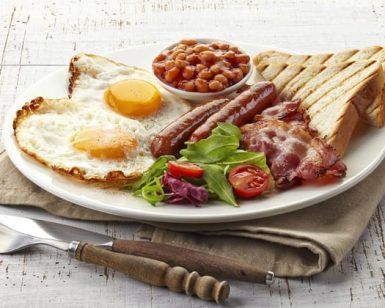 Disfrute de un brunch romántico en el Restaurante Gaztedi-Berria, que ofrece un desayuno inglés completo con huevos, tocino, salchichas, frijoles, tostadas y ensalada servido en un plato blanco con cubiertos. - ForTwo - Planes para parejas