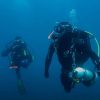 En el profundo mar azul de Castro Urdiales, Cantabria, dos buceadores con trajes de neopreno y equipo de buceo se deslizan elegantemente mientras experimentan su Bautismo de buceo en Castro Urdiales (Cantabria). - ForTwo - Planes para parejas
