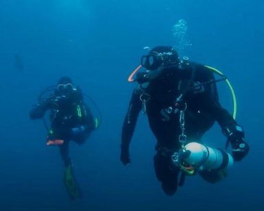 En el profundo mar azul de Castro Urdiales, Cantabria, dos buceadores con trajes de neopreno y equipo de buceo se deslizan elegantemente mientras experimentan su Bautismo de buceo en Castro Urdiales (Cantabria). - ForTwo - Planes para parejas