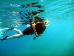 En medio de las brillantes aguas de Granada, una persona explora el vibrante mundo submarino con un cómodo traje de neopreno y un confiable snorkel desde "Salida de buceo snorkel desde barco en la costa de Granada", deslizándose sin esfuerzo con aletas a través de profundidades azules cristalinas. - ForTwo - Planes para parejas
