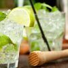 El Combinado de mojitos y pintxos únicos (Bilbao) cuenta con dos refrescantes cócteles de mojito con lima, menta y hielo, elegantemente presentados en una mesa con un mortero de madera, ideal para disfrutar de deliciosos pintxos. - ForTwo - Planes para parejas