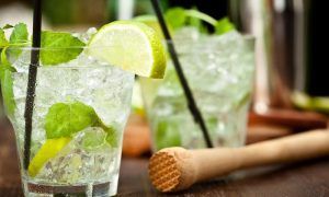 El Combinado de mojitos y pintxos únicos (Bilbao) cuenta con dos refrescantes cócteles de mojito con lima, menta y hielo, elegantemente presentados en una mesa con un mortero de madera, ideal para disfrutar de deliciosos pintxos. - ForTwo - Planes para parejas