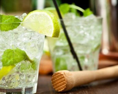 El Combinado de mojitos y pintxos únicos (Bilbao) cuenta con dos refrescantes cócteles de mojito con lima, menta y hielo, elegantemente presentados en una mesa con un mortero de madera, ideal para disfrutar de deliciosos pintxos. - ForTwo - Planes para parejas