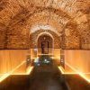 El Hotel Pestana Plaza Mayor de Madrid cuenta con un acogedor pasillo subterráneo de piedra con techos abovedados e iluminación cálida que conduce al relajante Circuito de spa con masaje para dos. - ForTwo - Planes para parejas