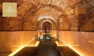 El Hotel Pestana Plaza Mayor de Madrid cuenta con un acogedor pasillo subterráneo de piedra con techos abovedados e iluminación cálida que conduce al relajante Circuito de spa con masaje para dos. - ForTwo - Planes para parejas