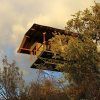 La Cabaña Aire en Dormir en los árboles en Cáceres ofrece una experiencia única de casa en un árbol, elevada sobre una ladera y enclavada entre árboles bajo un cielo parcialmente nublado. - ForTwo - Planes para parejas