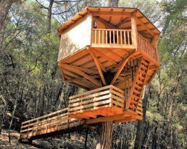 La Habitación mágica en los árboles de Cabanes Dosrius ofrece una casa de madera en el árbol con techo inclinado y balcón, enclavada entre altos árboles. Se accede por una escalera y una pasarela y captura el encanto de Barcelona. - ForTwo - Planes para parejas