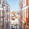 Explorar una calle estrecha en Mouraria, bordeada de edificios coloridos, revela un paisaje urbano pintoresco bajo un cielo azul claro como parte de la experiencia Visita a Mouraria y cena con concierto de fado (Lisboa). - ForTwo - Planes para parejas
