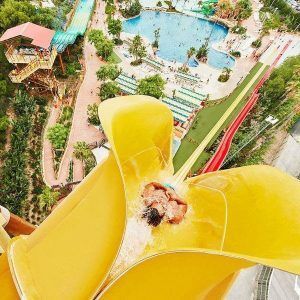 Un emocionante paseo por el gran tobogán acuático amarillo de Caribe Aquatic Park, rodeado de la exuberante vegetación de Port Aventura, crea un día inolvidable en Tarragona con Entradas para el parque acuático Caribe Aquatic Park de Port Aventura (Tarragona). - ForTwo - Planes para parejas