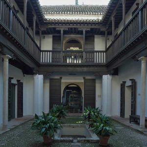 Este patio histórico, que hace eco de la elegancia de las Casas Nazaríes, cuenta con balcones de madera, plantas en macetas y un camino central que conduce a un arco, que recuerda a la Granada histórica: Explora los palacios y Casas Nazaríes frente a la Alhambra (Granada). - ForTwo - Planes para parejas