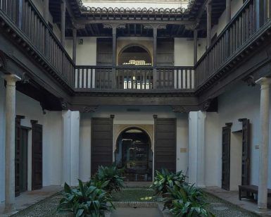 Este patio histórico, que hace eco de la elegancia de las Casas Nazaríes, cuenta con balcones de madera, plantas en macetas y un camino central que conduce a un arco, que recuerda a la Granada histórica: Explora los palacios y Casas Nazaríes frente a la Alhambra (Granada). - ForTwo - Planes para parejas