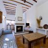 Relájese en una acogedora habitación en "Escapada en casa rural en el Parque Nacional de Sierra Nevada (Granada)", con sofás de cuadros azules, una mesa de madera y una chimenea. Disfrute de una decoración rústica con paredes blancas que evoca la encantadora sencillez granadina. - ForTwo - Planes para parejas