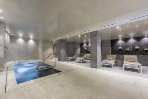 El moderno interior del spa del Hotel Cataluña ofrece una pequeña piscina, tumbonas e iluminación tenue. Los huéspedes podrán relajarse con la experiencia "Circuito de aguas, cava y masaje de esencias para parejas" en Granada. - ForTwo - Planes para parejas