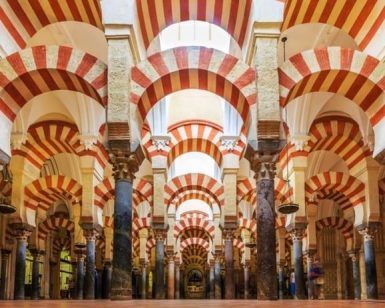 Explora el impresionante interior de la Mezquita-Catedral de Córdoba, donde los arcos rayados rojos y blancos coronan los pilares de mármol. Para una visión más profunda, considere el "Tour guiado con entradas: Mezquita-Catedral (Córdoba). - ForTwo - Planes para parejas