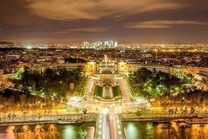 Experimente el encanto de una ciudad que recuerda a París al anochecer con edificios bien iluminados, un río resplandeciente y rascacielos distantes bajo un cielo nublado en el Tour romántico al anochecer por París. - ForTwo - Planes para parejas