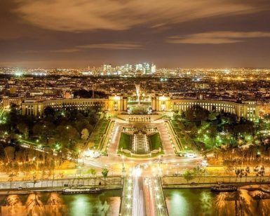 Experimente el encanto de una ciudad que recuerda a París al anochecer con edificios bien iluminados, un río resplandeciente y rascacielos distantes bajo un cielo nublado en el Tour romántico al anochecer por París. - ForTwo - Planes para parejas