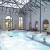 La piscina cubierta del Circuito Yhi Spa Meliá Villaitana (Alicante) cuenta con tumbonas, ventanas arqueadas con vigas de acero y elementos de agua en cascada, creando un ambiente sereno en este lujoso oasis. - ForTwo - Planes para parejas