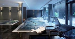 Lujoso spa interior en Valencia que cuenta con el Circuito Spa Primus 80 minutos de relax, que ofrece piscina, tumbonas, toallas y relajantes chorros de agua con paredes grises diseñadas por Primus e iluminación suave para una escapada serena. - ForTwo - Planes para parejas