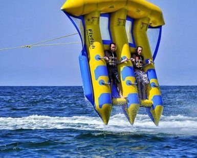 Dos personas viajan en un inflable amarillo y azul en el "Salta por los aires sobre el mar practicando el Flyfish en Barcelona" sobre el mar resplandeciente cerca de Barcelona. - ForTwo - Planes para parejas