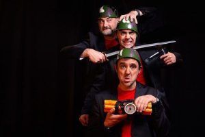 En el exterior del Teatro EDP Gran Vía de Madrid, tres hombres con casco posan dramáticamente con armas y un paquete de dinamita, evocando una escena de "Corta el cable rojo". - ForTwo - Planes para parejas