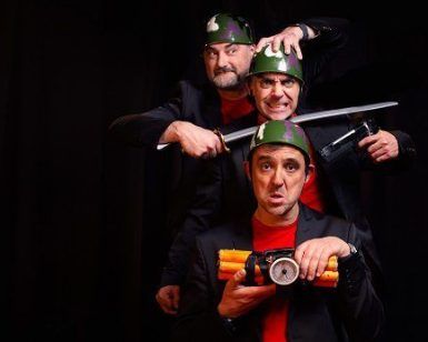 En el exterior del Teatro EDP Gran Vía de Madrid, tres hombres con casco posan dramáticamente con armas y un paquete de dinamita, evocando una escena de "Corta el cable rojo". - ForTwo - Planes para parejas