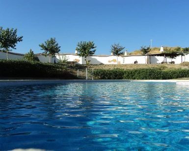 Ubicada en medio de una exuberante vegetación bajo un cielo azul, la serena piscina de Dos noches en cueva romántica con hammam y masaje (Guadix) ofrece una escapada tranquila cerca de su entrada a una cueva romántica. - ForTwo - Planes para parejas