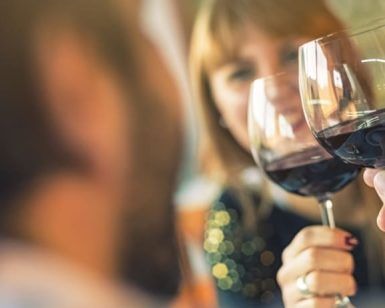 Dos personas brindando con vino tinto en un ambiente cálido y luminoso, dirigidos por un experto sumiller durante el "Curso de cata de vinos con un experto sumiller" en Madrid. - ForTwo - Planes para parejas