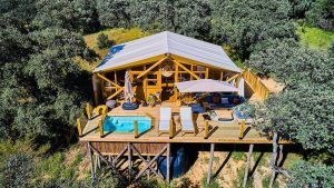 Vista aérea de la Cabaña junior suite con piscina privada en La Dehesa Experiences (Córdoba) que muestra una piscina privada, terraza y sillas de descanso en medio de árboles para un refugio exclusivo. - ForTwo - Planes para parejas