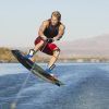 Una persona con un traje rojo practica wakeboard, elevándose sobre el agua en un día soleado, capturando la esencia de "Vive una auténtica experiencia de Wakeboard en Barcelona". - ForTwo - Planes para parejas
