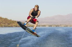 Una persona con un traje rojo practica wakeboard, elevándose sobre el agua en un día soleado, capturando la esencia de "Vive una auténtica experiencia de Wakeboard en Barcelona". - ForTwo - Planes para parejas