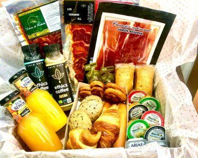 La canasta de regalo "Desayuno romántico a domicilio por Las Flores No se Comen" incluye paquetes de jamón, jugo, botellas de café, queso, pasteles y pães de queijo sobre un paño de lunares; ideal para un desayuno romántico a domicilio. - ForTwo - Planes para parejas