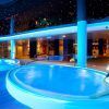 En el Hotel Diamante Beach, una mujer disfruta del moderno Circuito de Spa en Hotel Diamante Beach (Alicante) en una piscina cubierta iluminada en azul, bajo un techo estrellado que recuerda al sereno cielo nocturno de Alicante. - ForTwo - Planes para parejas