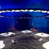 La sala azul futurista cuenta con una gran lámpara circular y exhibe el producto "Digital Impact" a través de su exhibición abstracta sobre una superficie texturizada. - ForTwo - Planes para parejas