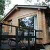 Ubicada en la exuberante vegetación de Cáceres, la Cabaña Musgo en Dormir en los Árboles ofrece un refugio tranquilo. La cabaña de madera se asienta sobre una plataforma con amplios ventanales y dos sillas negras en la terraza, ofreciendo un refugio idílico. - ForTwo - Planes para parejas