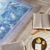 Un lujoso jacuzzi, dos sillas acolchadas y una pequeña mesa con un libro y una bebida sobre baldosas geométricas inspiradas en los elegantes años 20 crean el ambiente perfecto en Égoïste Spa. - ForTwo - Planes para parejas