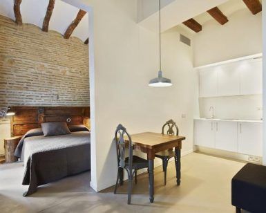 Encantador estudio con cama, pequeña mesa de comedor y cocina americana. Los detalles de ladrillo y madera aportan calidez. Ubicación ideal para disfrutar de aventuras enoturísticas con la Escapada de enoturismo de la mano del hotel Lotus Priorat en Falset (Tarragona). - ForTwo - Planes para parejas