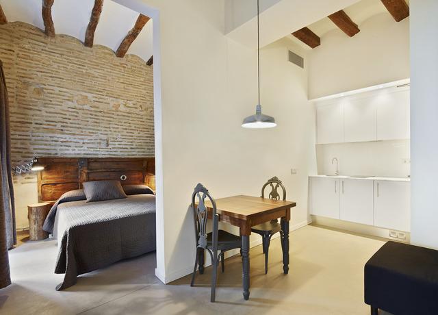 Encantador estudio con cama, pequeña mesa de comedor y cocina americana. Los detalles de ladrillo y madera aportan calidez. Ubicación ideal para disfrutar de aventuras enoturísticas con la Escapada de enoturismo de la mano del hotel Lotus Priorat en Falset (Tarragona). - ForTwo - Planes para parejas