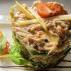 Una delicia culinaria: ensalada gourmet de atún con lechuga, tomates cherry y rodajas de manzana, rociada con salsa en un plato blanco, que evoca la elegancia del Restaurante Eustaquio Blanco (Cáceres). - ForTwo - Planes para parejas