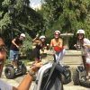 Cuatro personas en Segways, con cascos y sonrientes, posan en un parque con árboles y edificios mientras disfrutan de la pintoresca "Hacer una ruta en Segway por el Albaicín" a través del pintoresco paisaje. - ForTwo - Planes para parejas