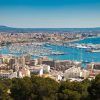 Una vista aérea de Palma de Mallorca revela una vibrante ciudad portuaria con barcos y edificios a lo largo de una resplandeciente costa azul. Cerca de allí, disfrute del lujo y relájese en el lujoso "Escapada con spa en el hotel HM Jaime III (Palma de Mallorca)" tras explorar los vibrantes alrededores. - ForTwo - Planes para parejas